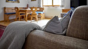 Ett vardagsrum med en soffa, ett matbord med stolar och en tv.