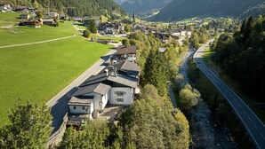 A mountainous village with traditional houses, a river, and a road. - 1302 Alt Montafon Appartment 2 (Gaschurn)
