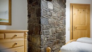 A room with a stone wall, wooden dresser, and a wooden door. - 1302 Alt Montafon Appartment 2 (Gaschurn)