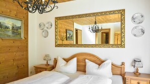 Une chambre à coucher avec une tête de lit en bois, un grand miroir, des tables de chevet et un lustre.