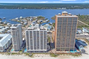 Een hoog hotel met meerdere verdiepingen, een zwembad en uitzicht op een meer en strand.