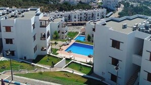 Un quartier résidentiel avec des bâtiments blancs, une piscine et une vue sur la mer.
