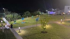 Un espace extérieur bien éclairé, agrémenté d’un sentier, de petits arbres et de sculptures colorées.