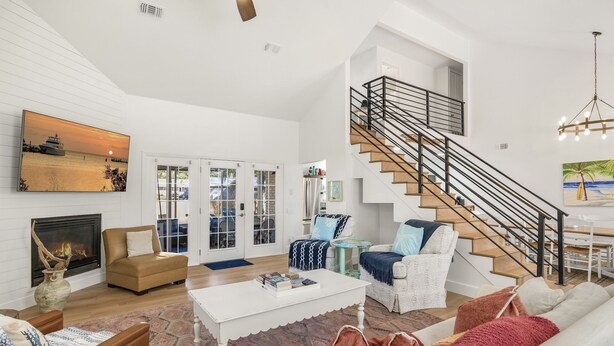A spacious living room with a high ceiling, a staircase, and a large window overlooking a balcony. - Private Pool | 6-Seater LSV | Garage (Santa Rosa Beach)