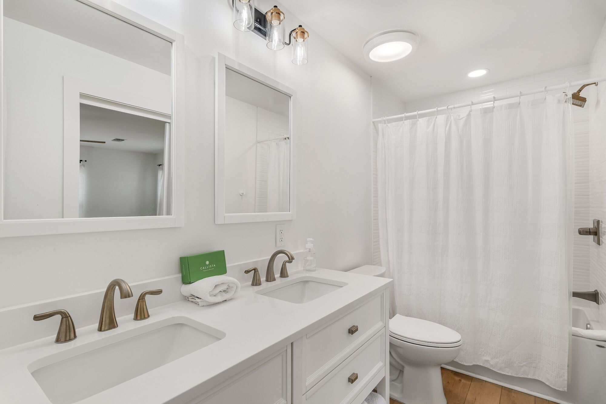 A modern bathroom with two sinks, a toilet, and a shower curtain.
