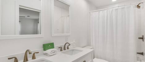 A modern bathroom with two sinks, a toilet, and a shower curtain.