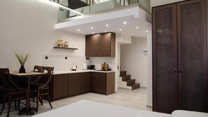 A modern kitchen with a central island, wooden cabinets, and a dining area with chairs. - Leone Suites (Nafpaktos)