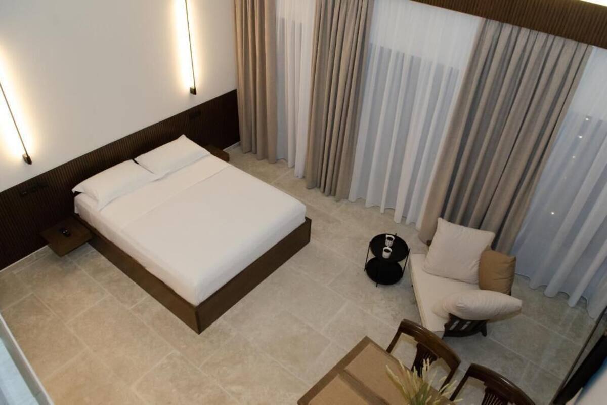 A hotel room with a large bed, a small round table, a chair, and a sofa.
