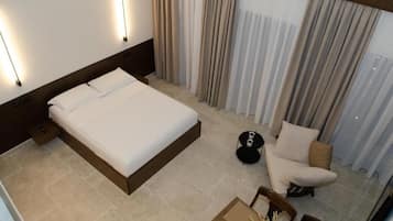 A hotel room with a large bed, a small round table, a chair, and a sofa.