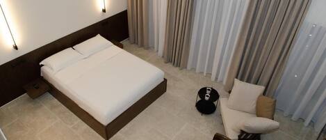 Habitació d'hotel amb un llit gran, una taula rodona petita, una cadira i un sofà.