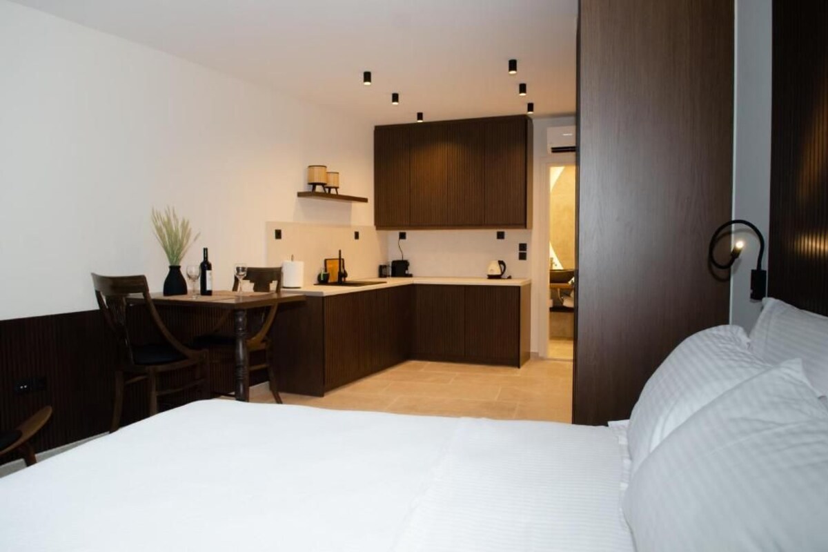 A modern hotel room with a bed, a desk, and a kitchenette.