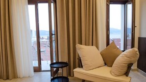 A room with a sofa, a small round table, and a view through a glass door. - Leone Suites (Nafpaktos)