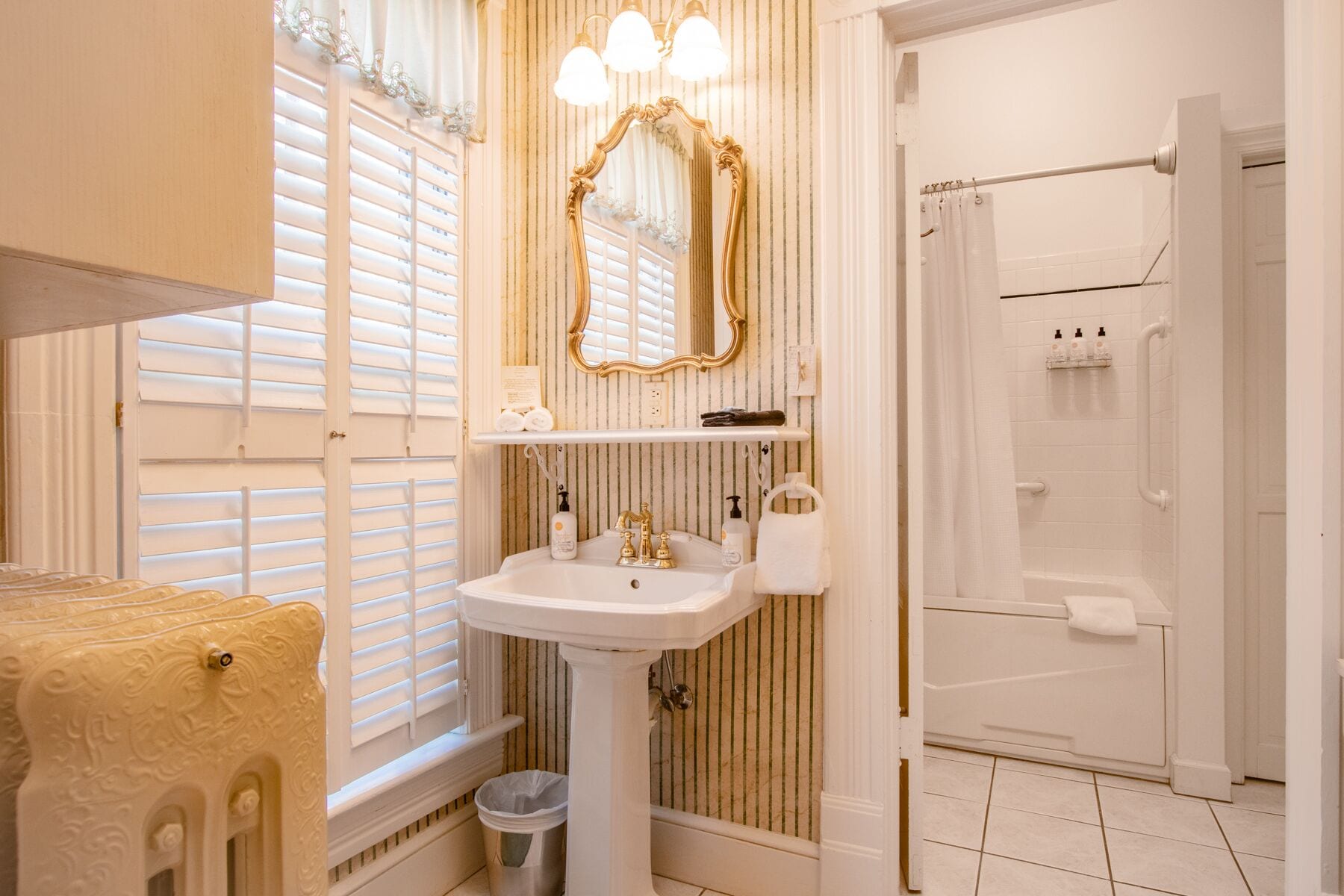 A bathroom with a pedestal sink, a large mirror, and a shower area.