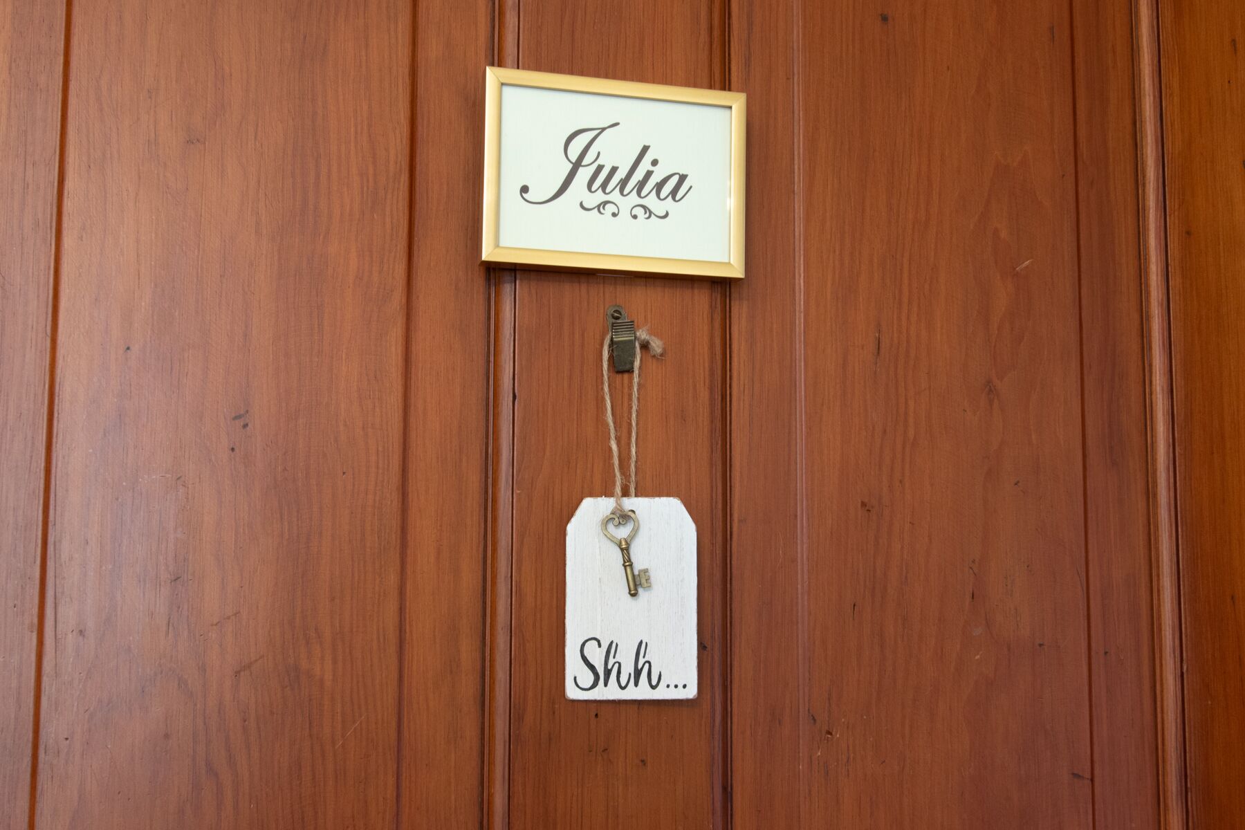 A wooden door with a framed nameplate reading "Julia" and a tag hanging below it with the text "Shh...".