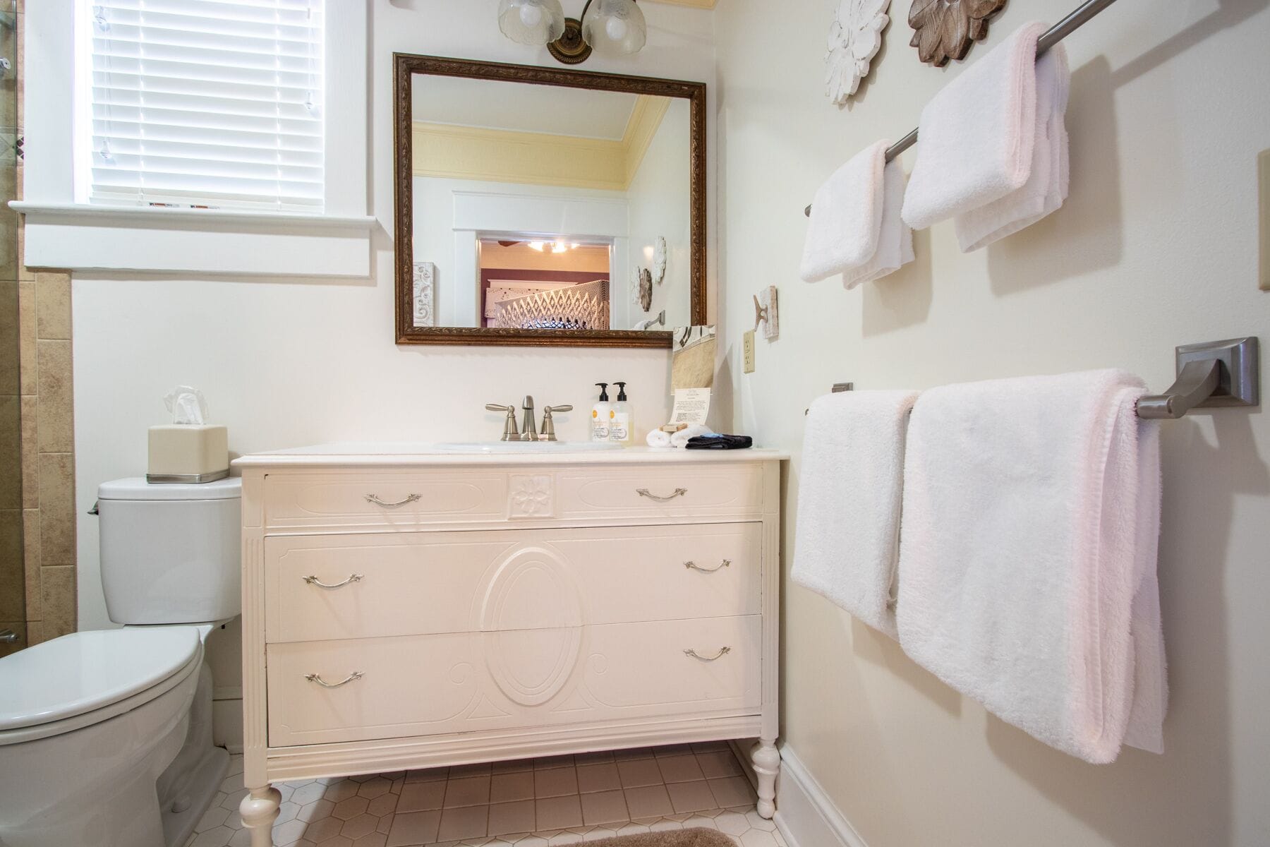 A bathroom with a toilet, a vanity with a mirror, and towels on a rack.