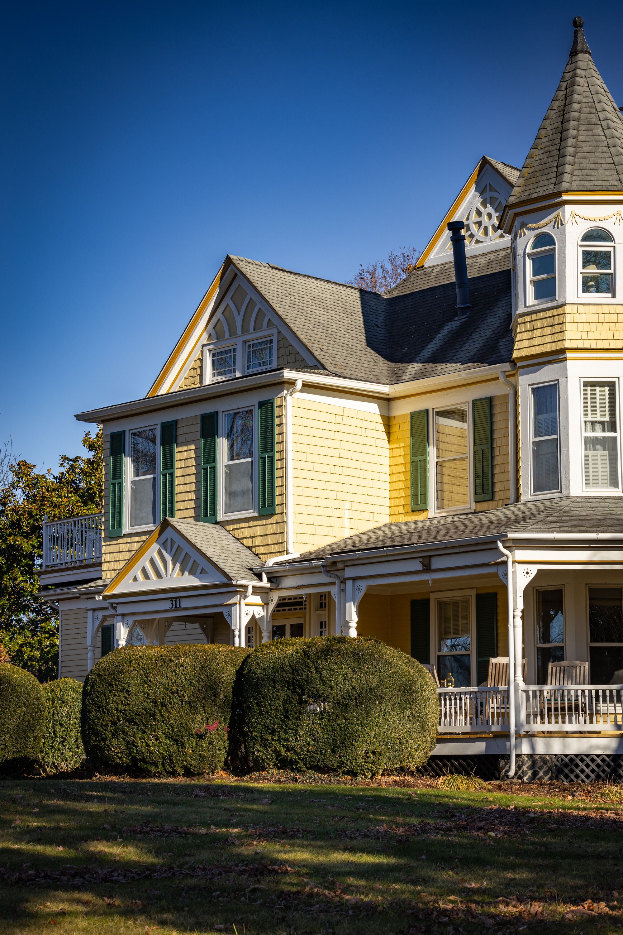 A large, two-story house with a prominent tower and a wrap-around porch.