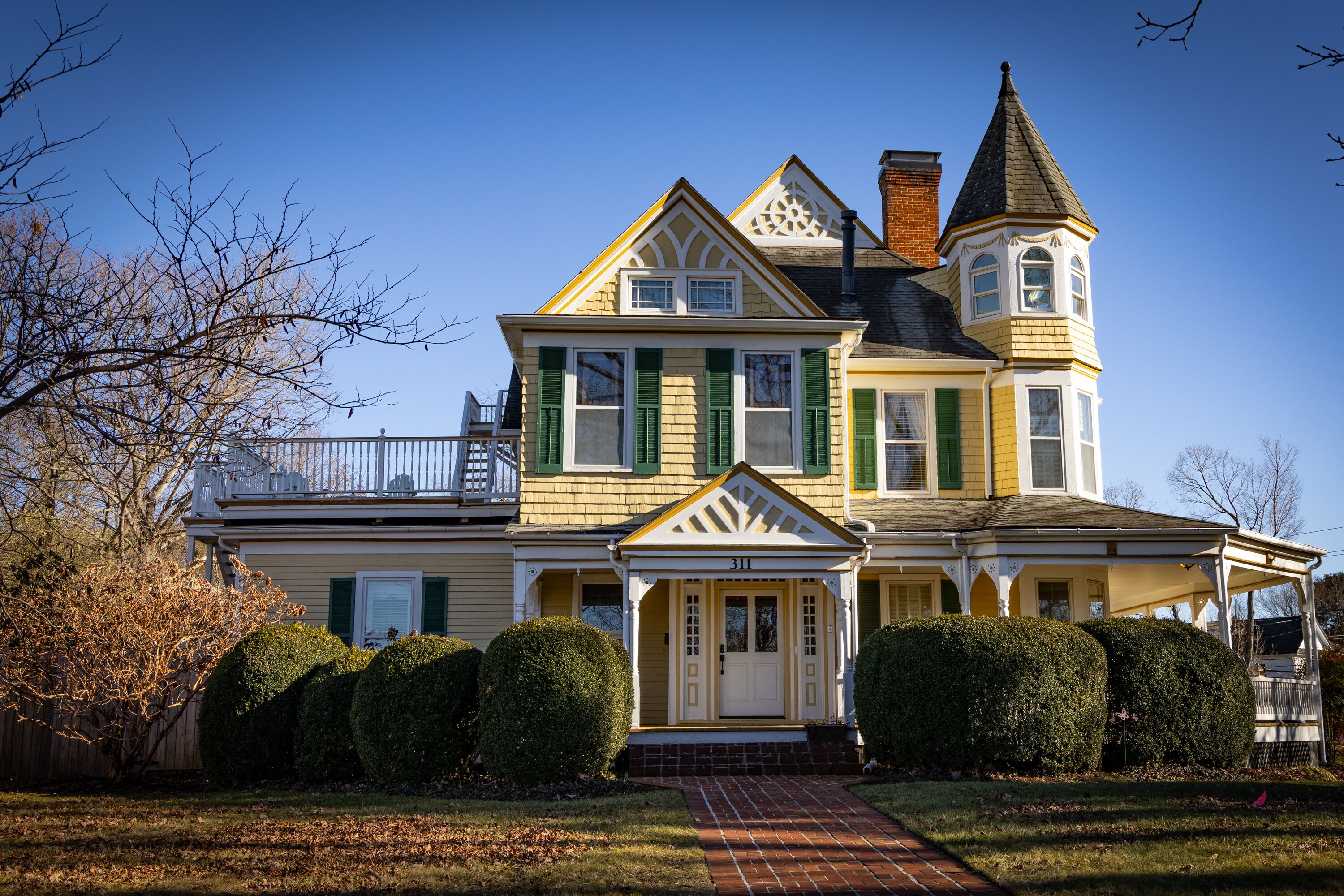A large, two-story house with a prominent tower and a wrap-around porch.
