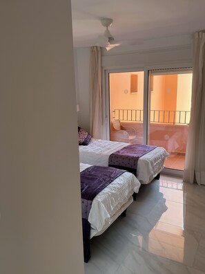 A hotel room with two beds, a balcony with a railing, and a view of the outside. - Completely refurbished 2 bedroom apartment 5 min walk to 1st tee and Hotel (Torre-Pacheco)