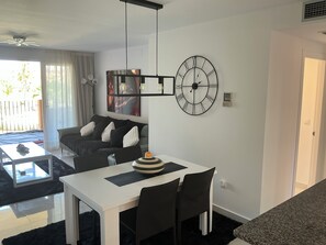 A modern living room with a dining area, a large wall clock, and a ceiling fan. - Completely refurbished 2 bedroom apartment 5 min walk to 1st tee and Hotel (Torre-Pacheco)