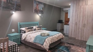 A bedroom with a bed, a nightstand, a chair, and a wardrobe. - Wisteria Lane Guesthouse (Tsantsabane)