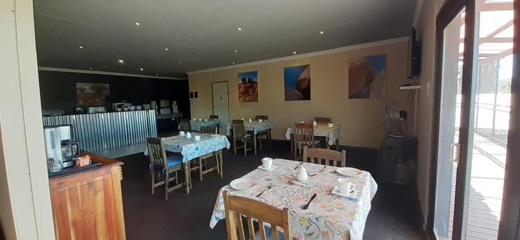 A dining area with tables set for service, a counter with a menu, and a view of the outdoors.