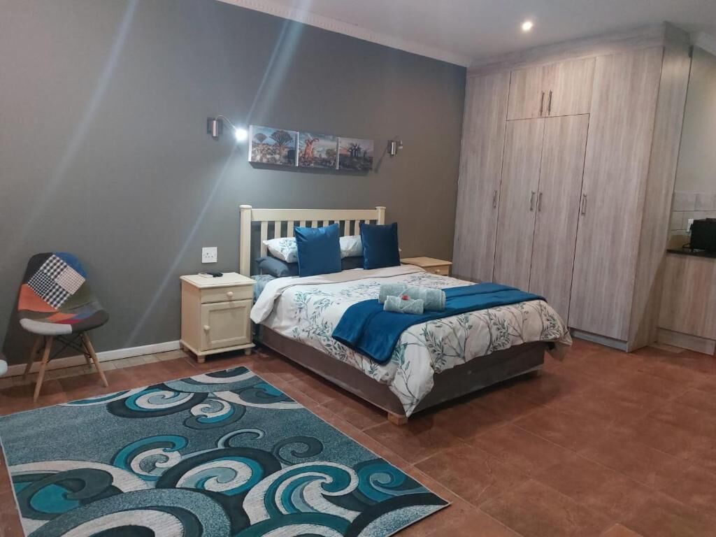 A bedroom with a bed, nightstands, a chair, a wardrobe, and a patterned rug.