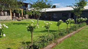 A residential property with a well-maintained lawn, a pathway, and a variety of flowering plants. - Wisteria Lane Guesthouse (Tsantsabane)