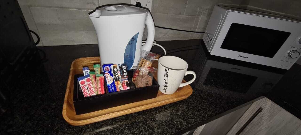 Un comptoir de cuisine sur lequel se trouve un plateau contenant divers aliments, une tasse blanche et un four à micro-ondes.