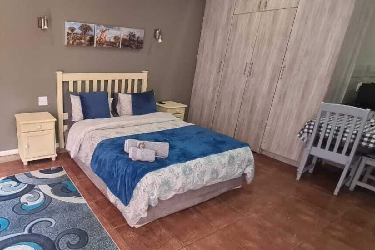 A bedroom with a bed, nightstands, a chair, a table, and a wardrobe.
