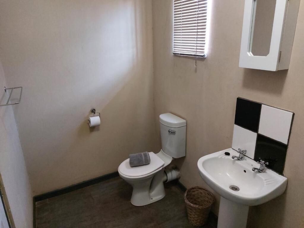 A small bathroom with a toilet, sink, and a mirror.