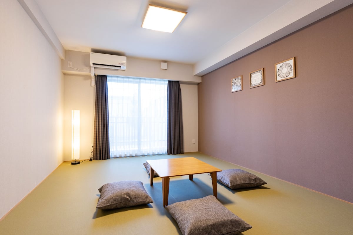 A room with tatami flooring, a low wooden table, and cushions.