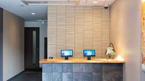 A reception desk with two monitors, a wooden slat wall, and a tiled floor. - HOTEL ECCLESIA (Kyoto)