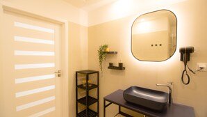 A bathroom with a sink, mirror, shelf, and towel rack. - Luxury Apartment in the heart of Vienna  (Vienna)