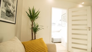 A modern living room with a sofa, a yellow pillow, a potted plant, and a framed photo on the wall. - Luxury Apartment in the heart of Vienna  (Vienna)