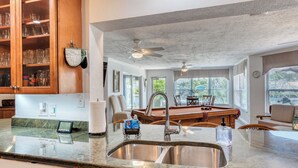 Une cuisine dotée de plans de travail en granit, d’un évier en acier inoxydable, de meubles en bois et d’une cave à vin intégrée.