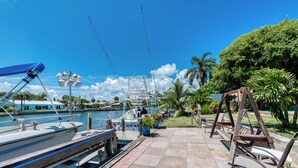 Un port de plaisance avec des bateaux amarrés, une balançoire en bois et un ciel bleu azur.