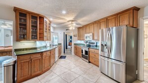 Une cuisine moderne avec des meubles en bois, des appareils électroménagers en acier inoxydable et un sol carrelé.