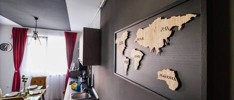 Una cocina moderna con comedor, un mapa del mundo en la pared y una ventana con cortinas rojas.
