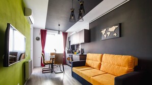 Un salon moderne avec un canapé, un coin repas avec des chaises, un espace cuisine et une carte du monde accrochée au mur.