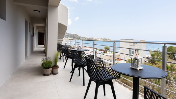 A balcony with outdoor seating, potted plants, and a view of the sea. - Niro Beachfront Living (Hersonissos)