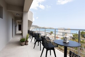 A balcony with outdoor seating, potted plants, and a view of the sea. - Niro Beachfront Living (Hersonissos)