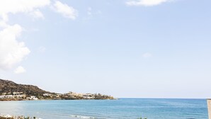 A coastal view with buildings on a hillside, a clear sky, and calm sea. - Niro Beachfront Living (Hersonissos)