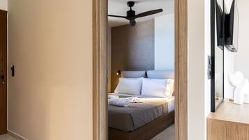 Een moderne slaapkamer met een houten bedframe, een plafondventilator en een nachtkastje met spiegel.