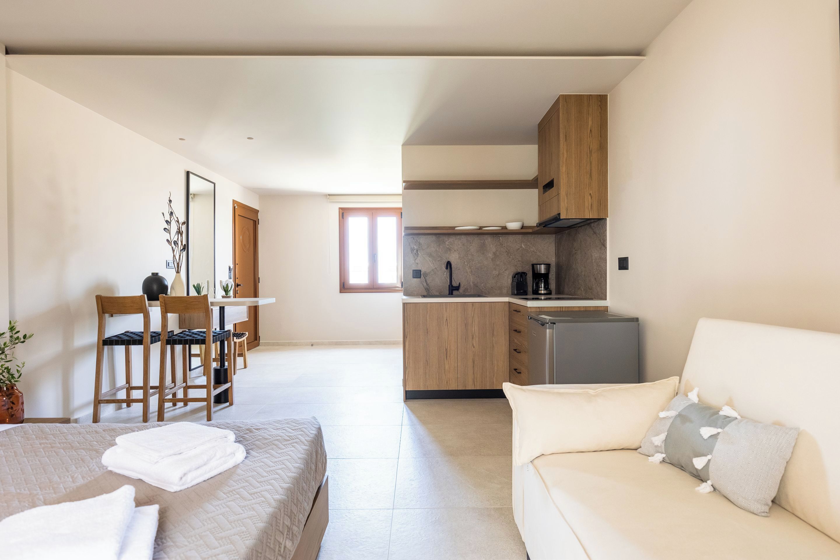 Una habitación de hotel moderna con cama, sofá, zona de comedor y cocina.