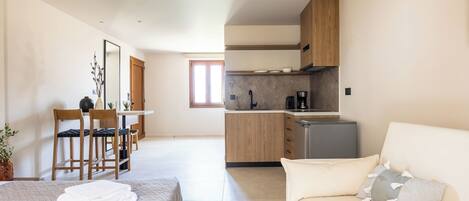 Una habitación de hotel moderna con cama, sofá, zona de comedor y cocina.