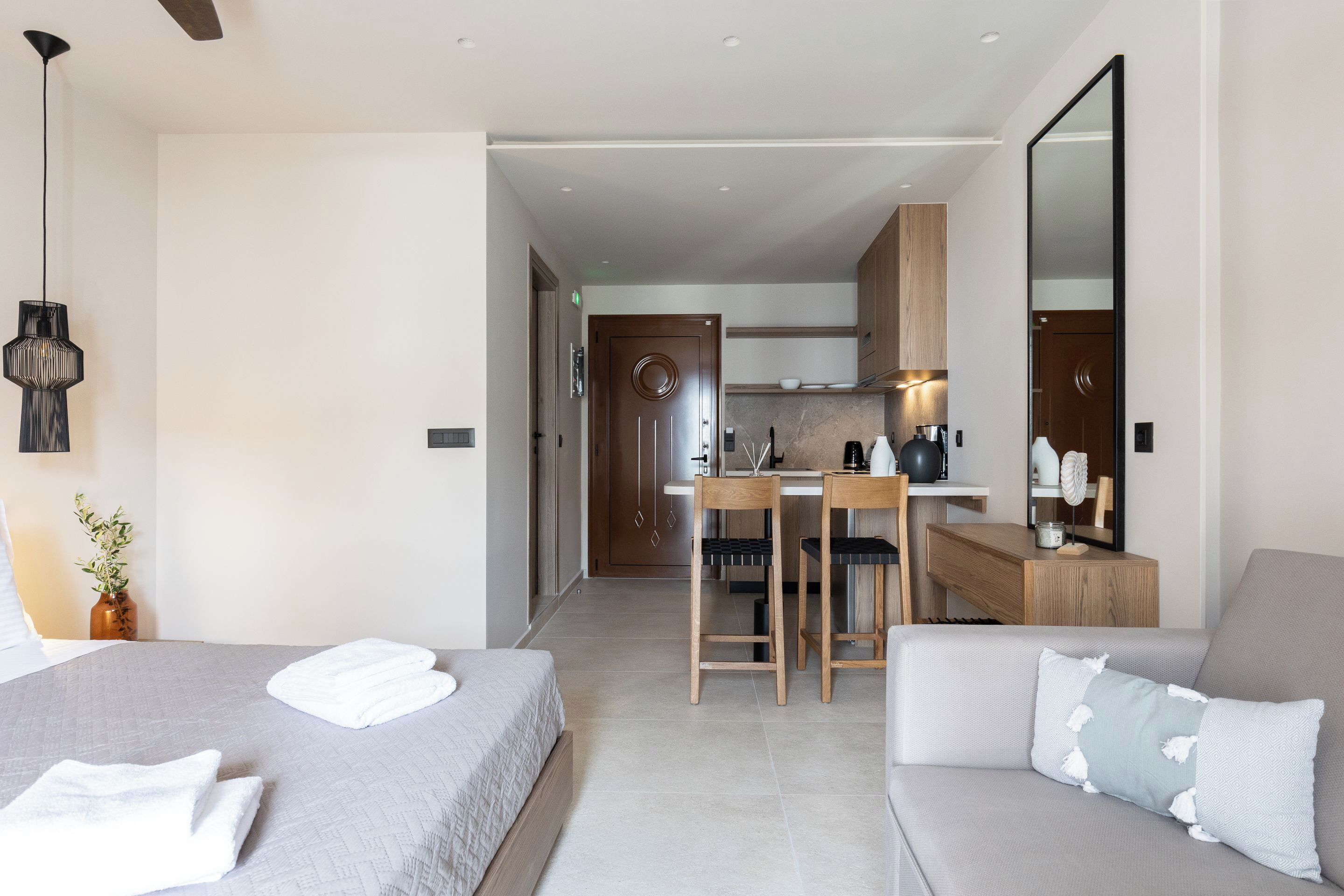 Une chambre d’hôtel moderne équipée d’un lit, d’un canapé, d’un bureau et d’un coin cuisine.