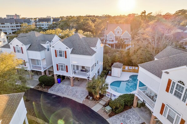 A residential area with multiple houses, a swimming pool, and a clear sky.