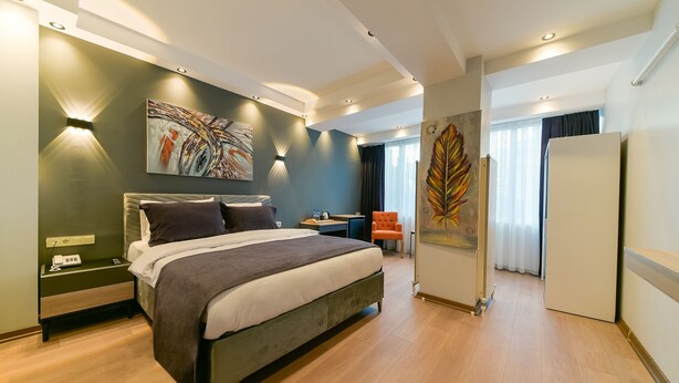 A modern bedroom with a large bed, bedside tables, a desk, and a chair. - Rise Inn  (Istanbul)