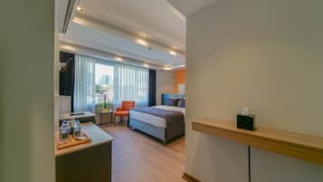 A hotel room with a bed, a desk with water bottles, a chair, and a TV.