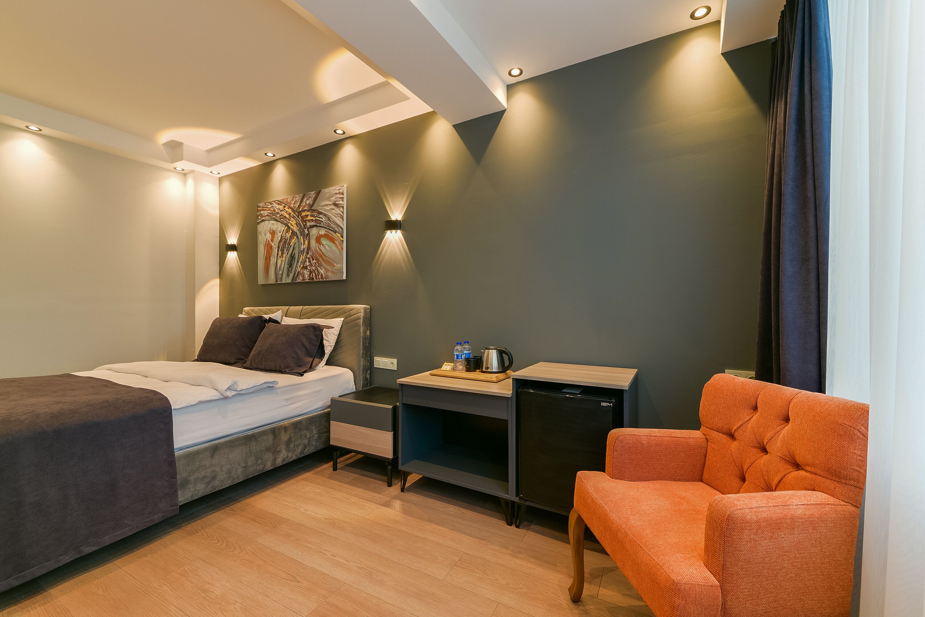 Una habitación de hotel pequeña con cama, escritorio, silla y una kitchenette.
